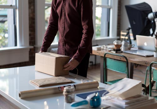 Small business owner with box and measuring tape in an office