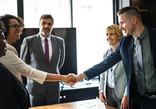 Professional people in business attire shaking hands in a well-lit room.